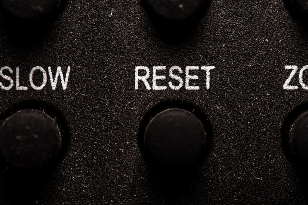 Detalhe do botão reset em controle remoto de Smart TV, destacando a tecla para reinicialização rápida do sistema